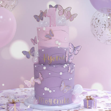 Luxury pink and purple butterfly 1st birthday cake by CakeObsession in Basildon Essex with personalised gold name charms and pastel butterfly decorations.