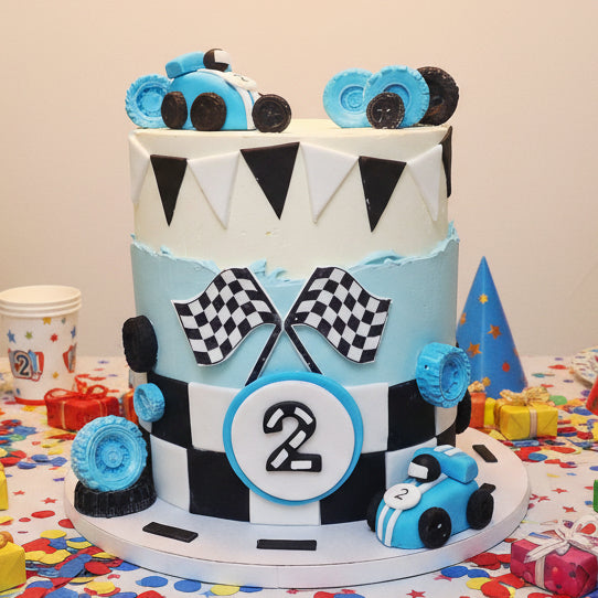 Race car themed kids birthday cake with fondant race cars and checkered flags, handmade in Basildon Essex by Cake Obsession.