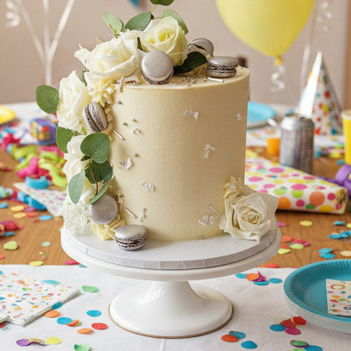 Elegant White Rose Celebration Cake adorned with silk white roses, edible silver or gold accents, and macarons, handmade and personalised, perfect for birthdays, anniversaries, weddings, and special occasions, available for delivery in Basildon and Essex.