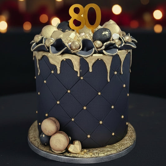 A luxury-style birthday cake in black and gold. Gold drip icing, and gold and black decorative toppers on top.