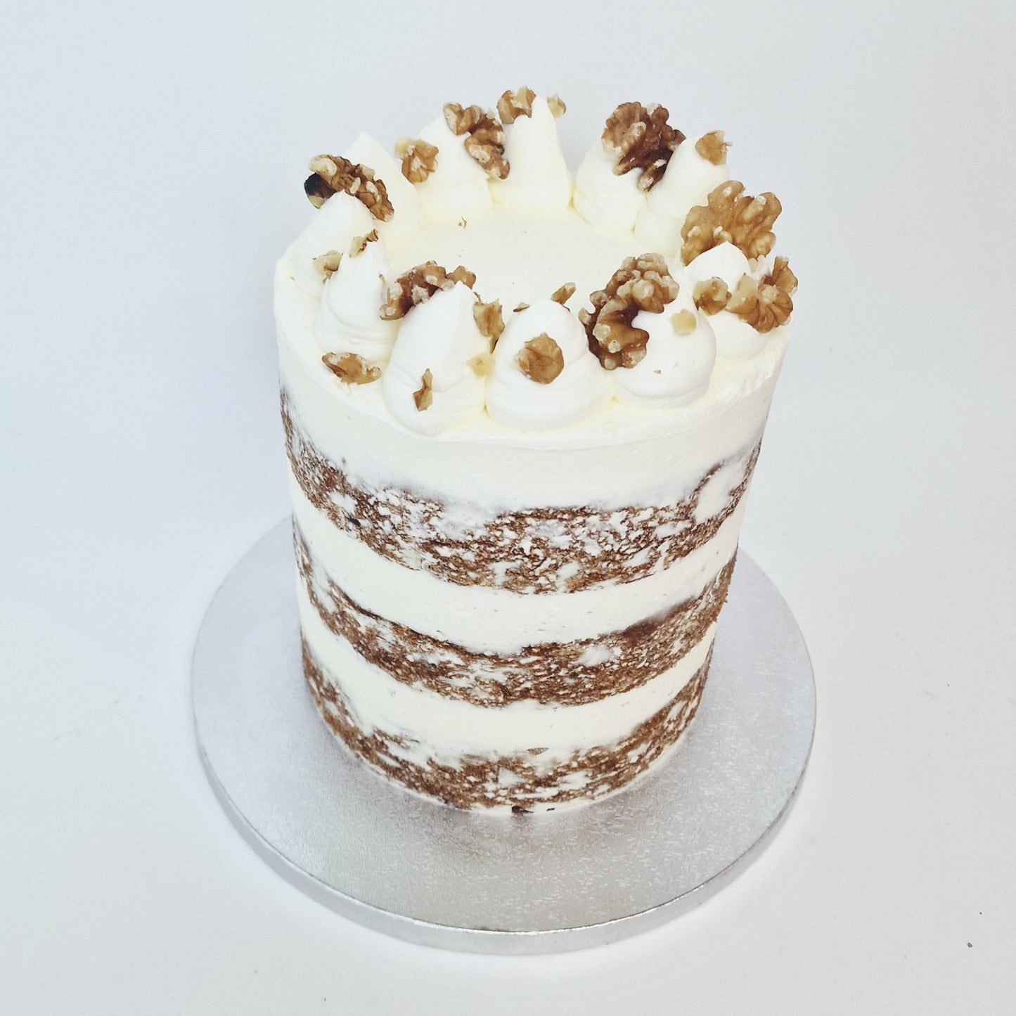 Layered cake with white frosting and walnuts on a white background
