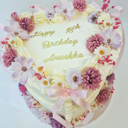 Heart-shaped birthday cake with flowers and 'Happy 18th Birthday Avishka' text on a white background