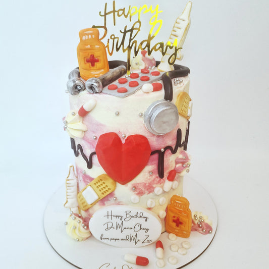 Birthday cake with medical-themed decorations and 'Happy Birthday' topper on a white background