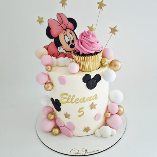 Birthday cake with Minnie Mouse theme and pink cupcake on a white background