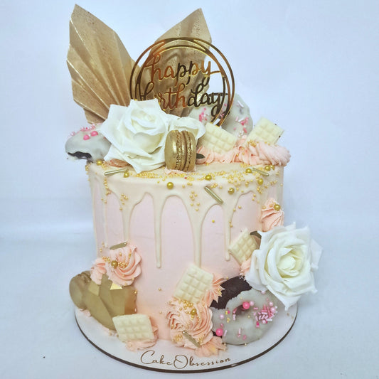 This exquisite pink cake is adorned with two golden fans and silk roses, creating a stunning visual display. It features a luscious white chocolate drip, golden macaroons, and a heart-shaped accent for added elegance. A perfect choice for a romantic or celebratory occasion.