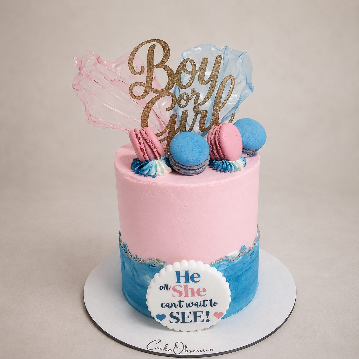 Luxury gender reveal cake in Basildon Essex with pink and blue buttercream, macarons and gold boy or girl topper by CakeObsession