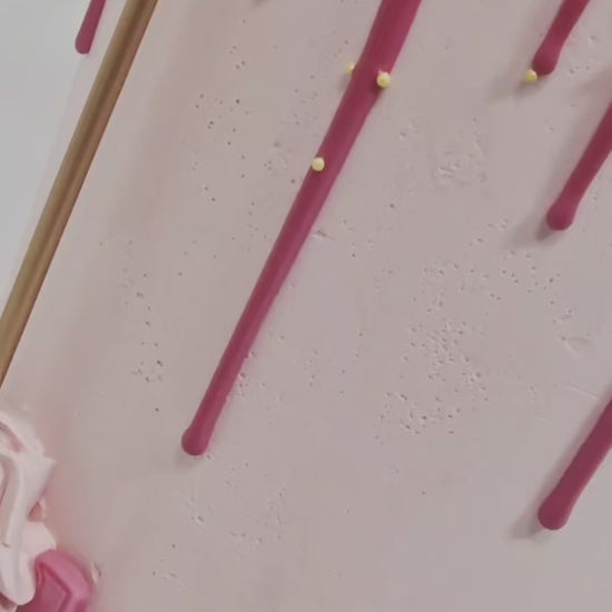 Pretty in Pink Celebration Cake with smooth baby pink buttercream, hot pink drip, cupcake topper, mini hearts, chocolates, and golden candle, handmade and personalised, perfect for birthdays, anniversaries, and special celebrations, available for delivery in Basildon and Essex.