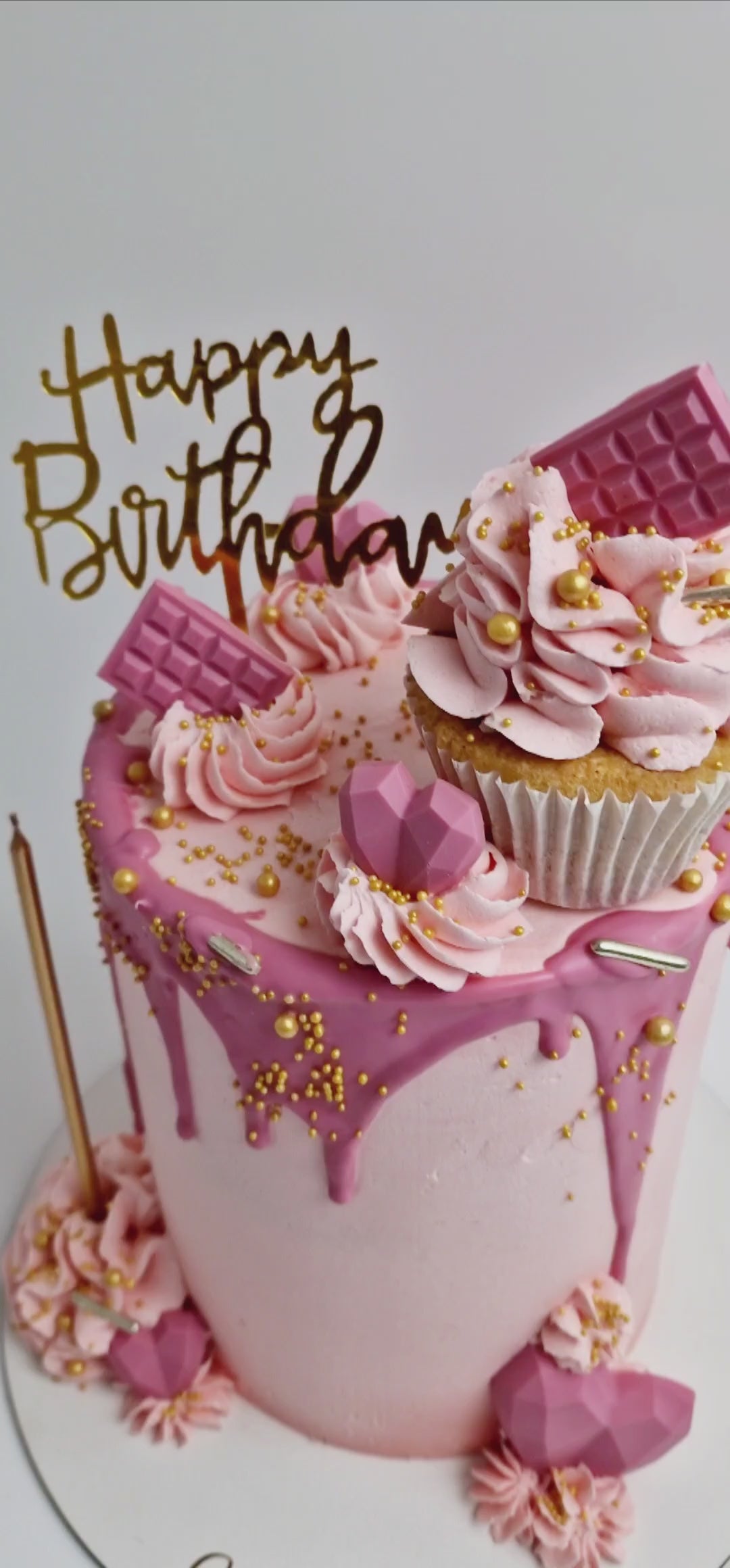 Pretty in Pink Celebration Cake with smooth baby pink buttercream, hot pink drip, cupcake topper, mini hearts, chocolates, and golden candle, handmade and personalised, perfect for birthdays, anniversaries, and special celebrations, available for delivery in Basildon and Essex.