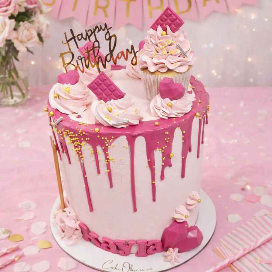 Pretty in Pink Celebration Cake with smooth baby pink buttercream, hot pink drip, cupcake topper, mini hearts, chocolates, and golden candle, handmade and personalised, perfect for birthdays, anniversaries, and special celebrations, available for delivery in Basildon and Essex.