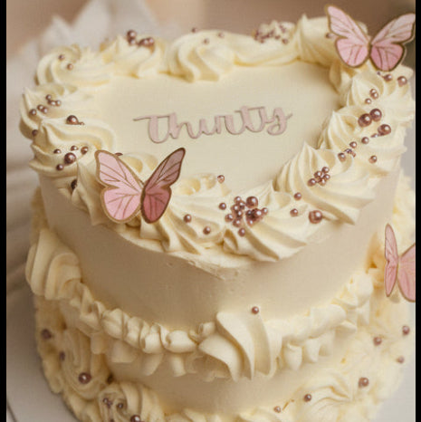 Pink two tier princess castle birthday cake with buttercream ruffles, princess images and golden castle topper, available from CakeObsession in Essex.