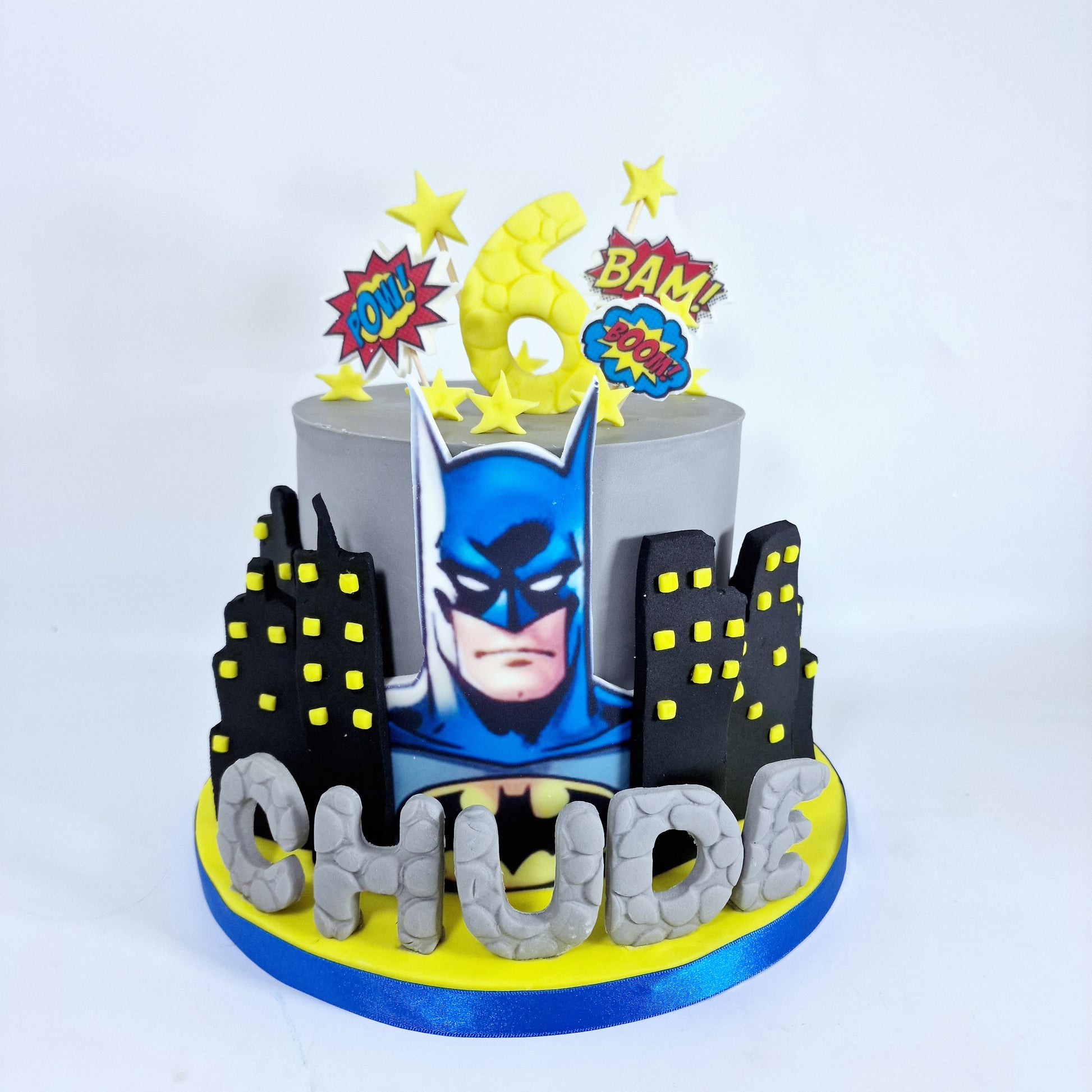 A themed birthday cake decorated to look like the Batman character, with a cityscape background.